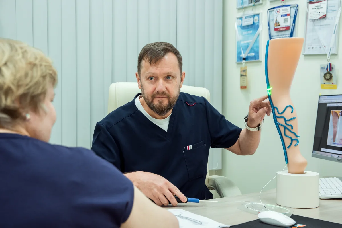 Доктор Семенов объясняет пациентке лечение на модели вен